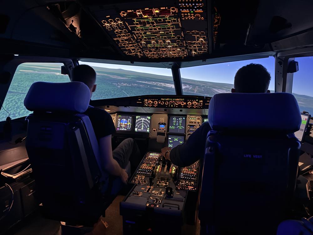 Zwei Teilnehmer steuern den Airbus im Simulator über eine Küstenlandschaft