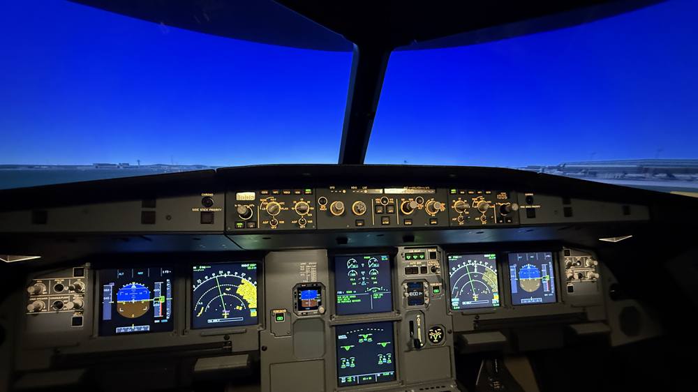Airbus-Cockpit im Simulator in der Abenddämmerung: tiefblauer Himmel über dem Flughafen, darunter Glareshield und Displays
