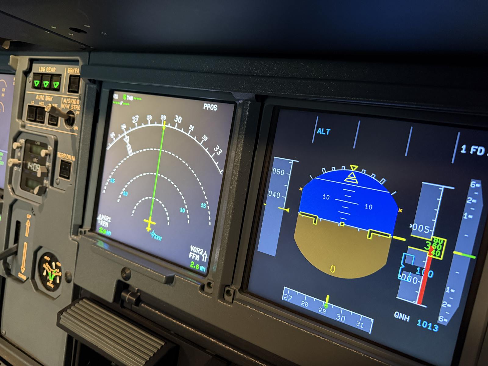 Navigation Display und Primary Flight Display im Airbus-Cockpit des Level-D-Simulators, links daneben die Fahrwerksanzeige mit drei grünen Lampen